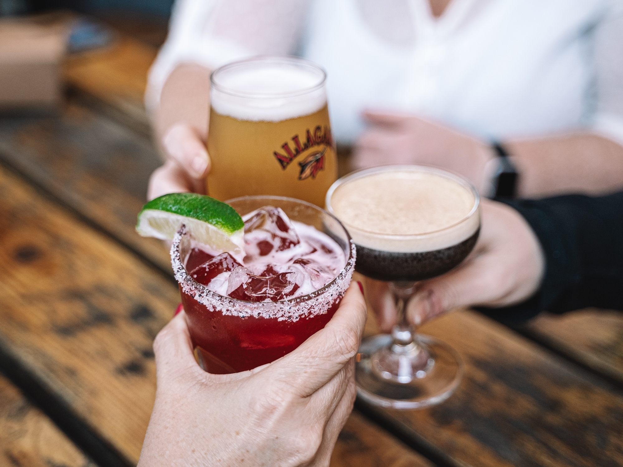 Friends toasting with a beer, a cocktail and an espresso martini