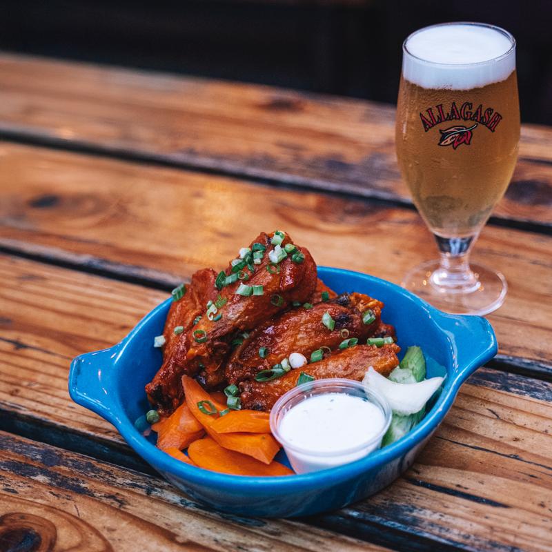 Buffalo chicken wings with carrots and a beer