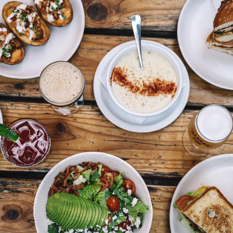 Clam chowder, a salad, potato skins and drinks on a wooden table