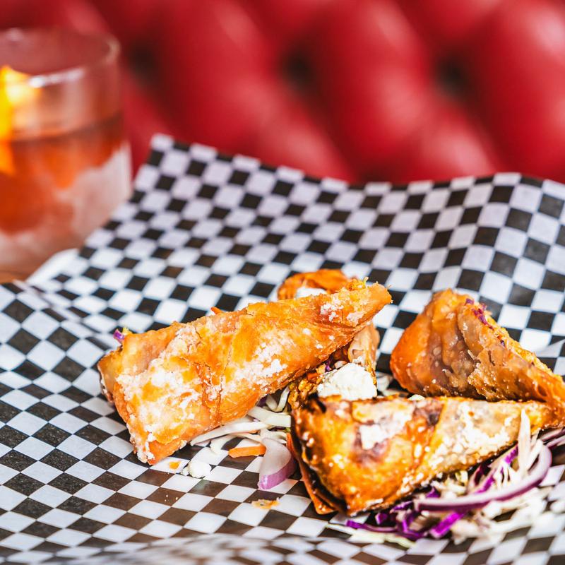 Buffalo Chicken Eggrolls with a cocktail in the background