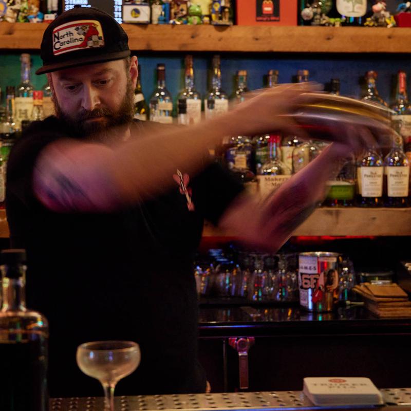 Bartender in a cap shaking a cocktail