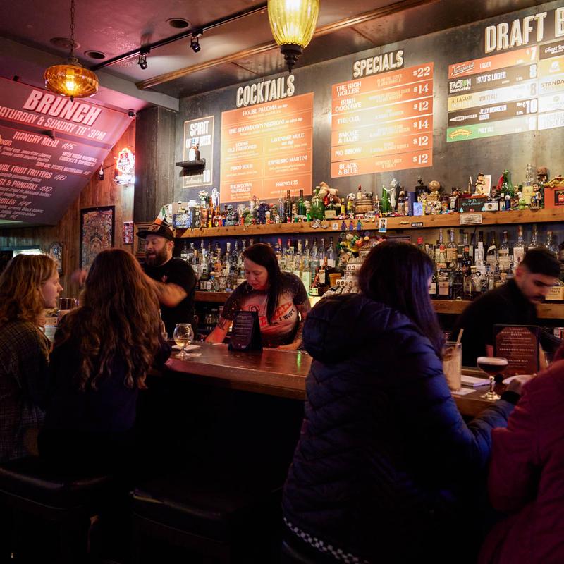 Guests at the bar under the cocktail, specials and draft boards