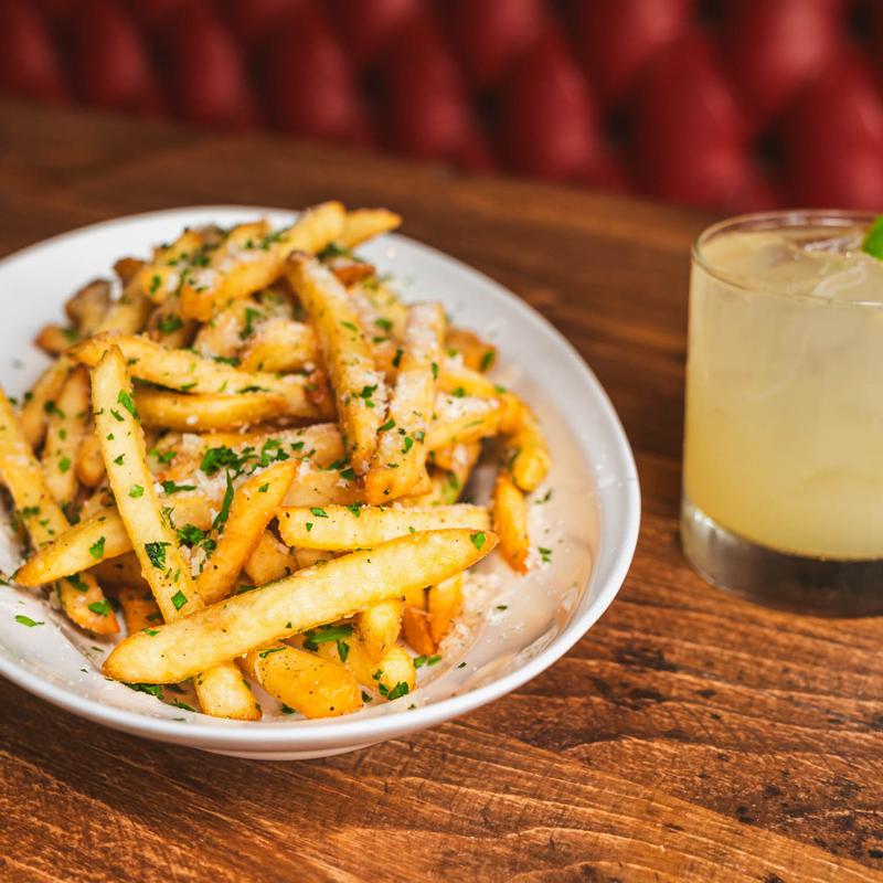 Garlic fries on a table next to a cocktail