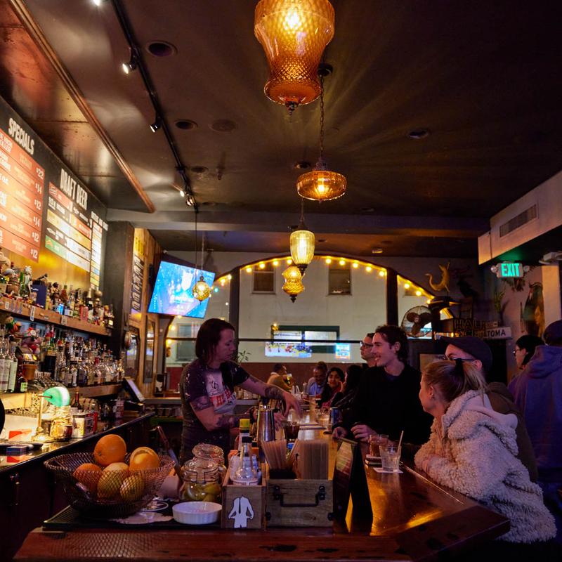 The long bar under hanging lamps, with guests and a game on