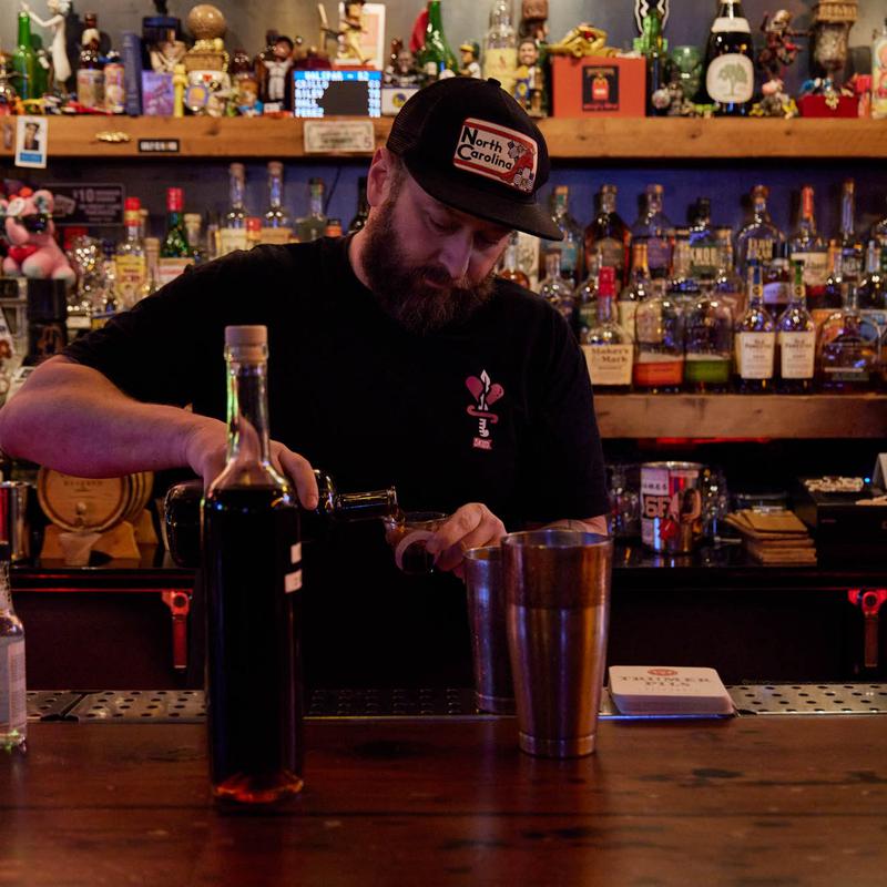 Bartender in a cap pouring at the back bar