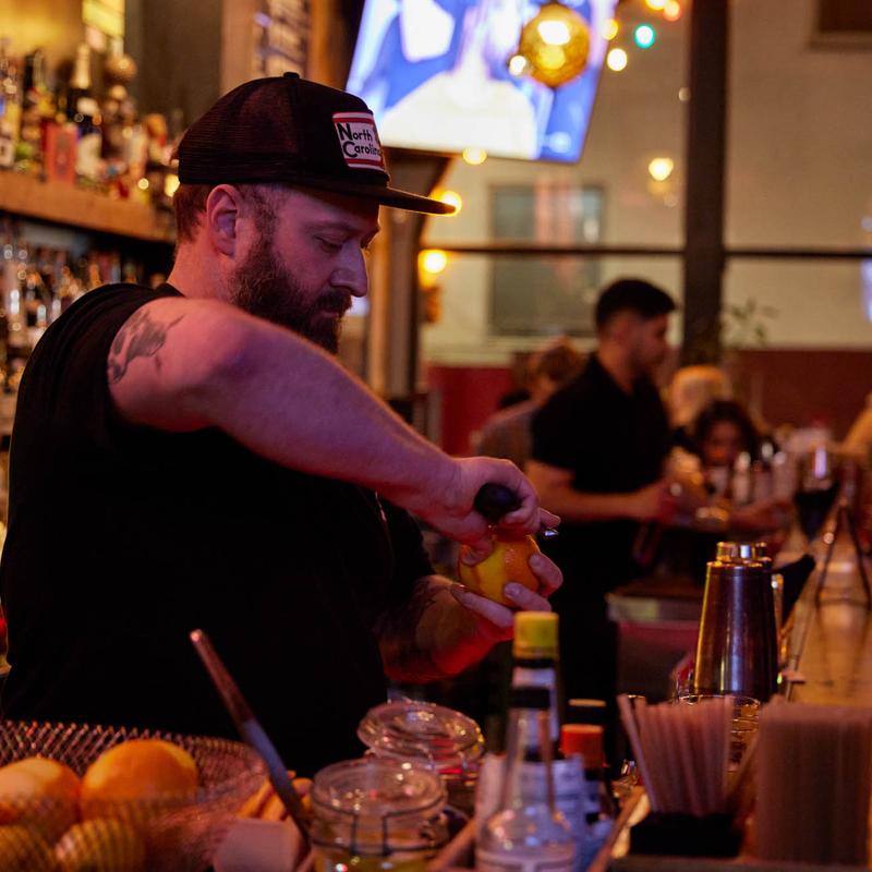 Bartender in a cap garnishing a drink