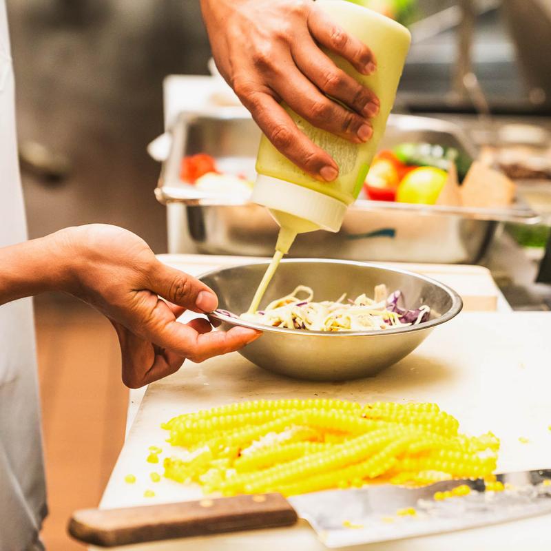 Hands pouring dressing over a salad