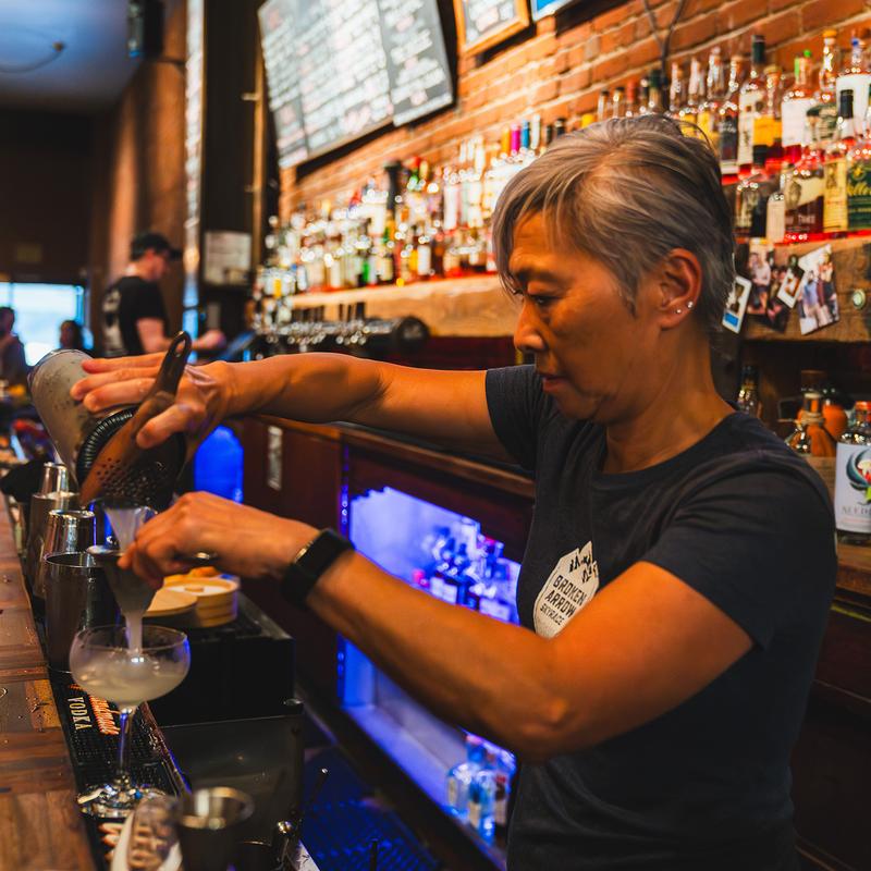 Bartender straining a cocktail into a glass