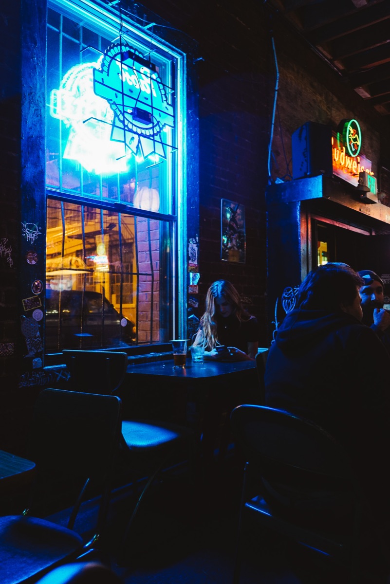Booth seating washed in blue neon light from the front windows