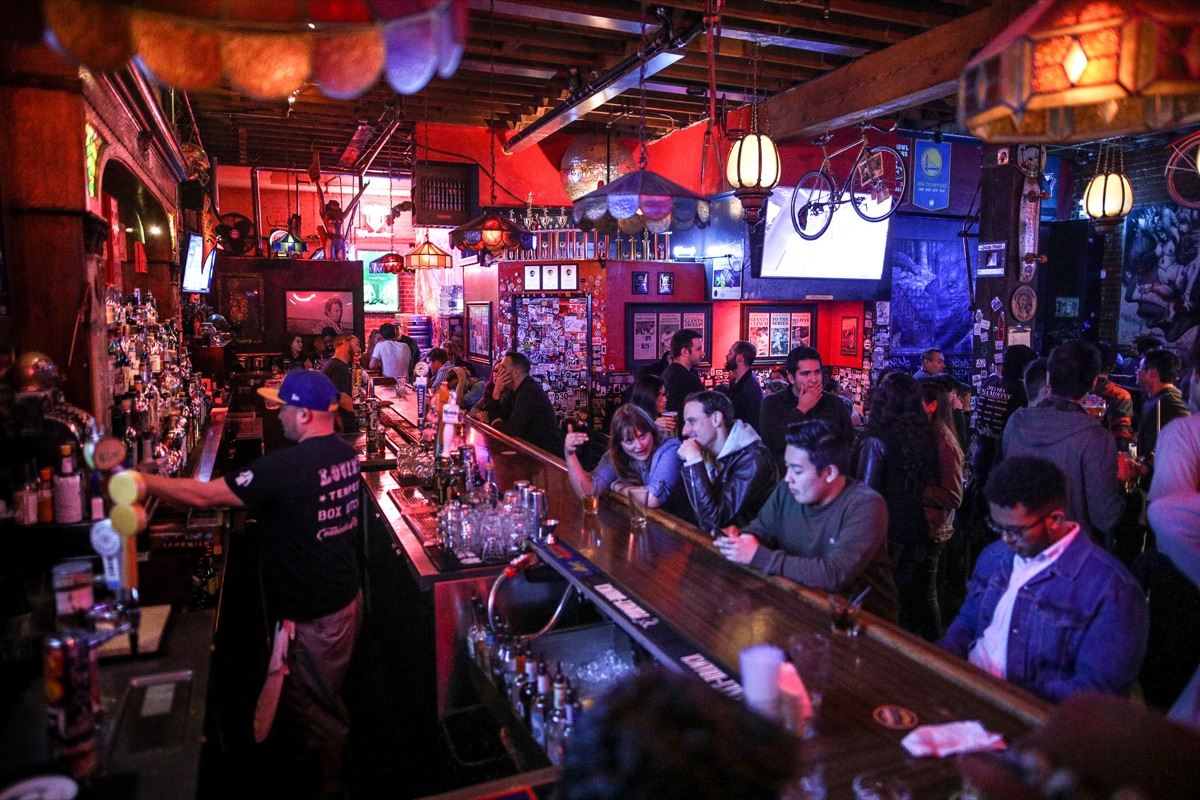 Bartender working the taps with regulars lining the bar top