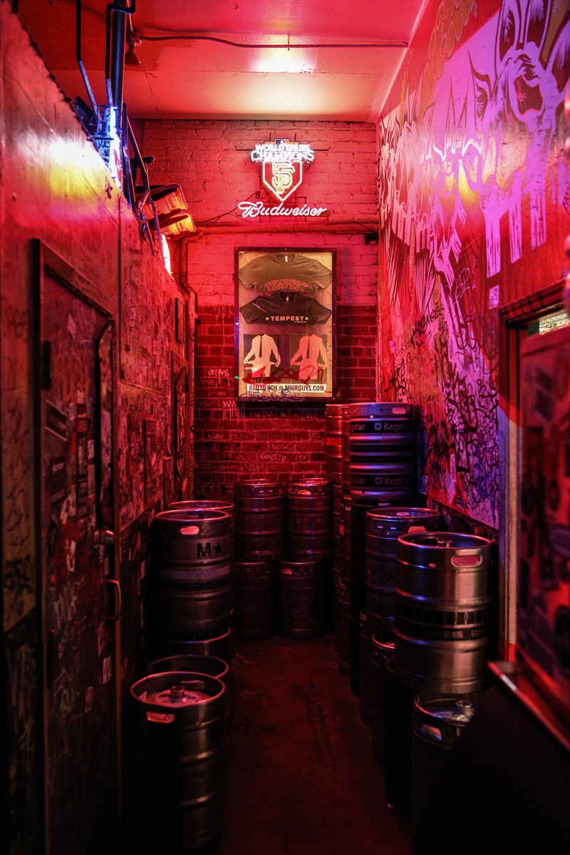 The red-lit back hallway stacked with kegs