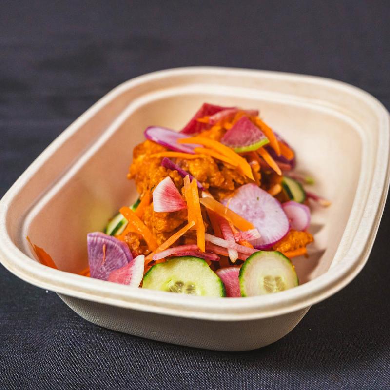 Popcorn chicken in a to-go bowl with pickled vegetables